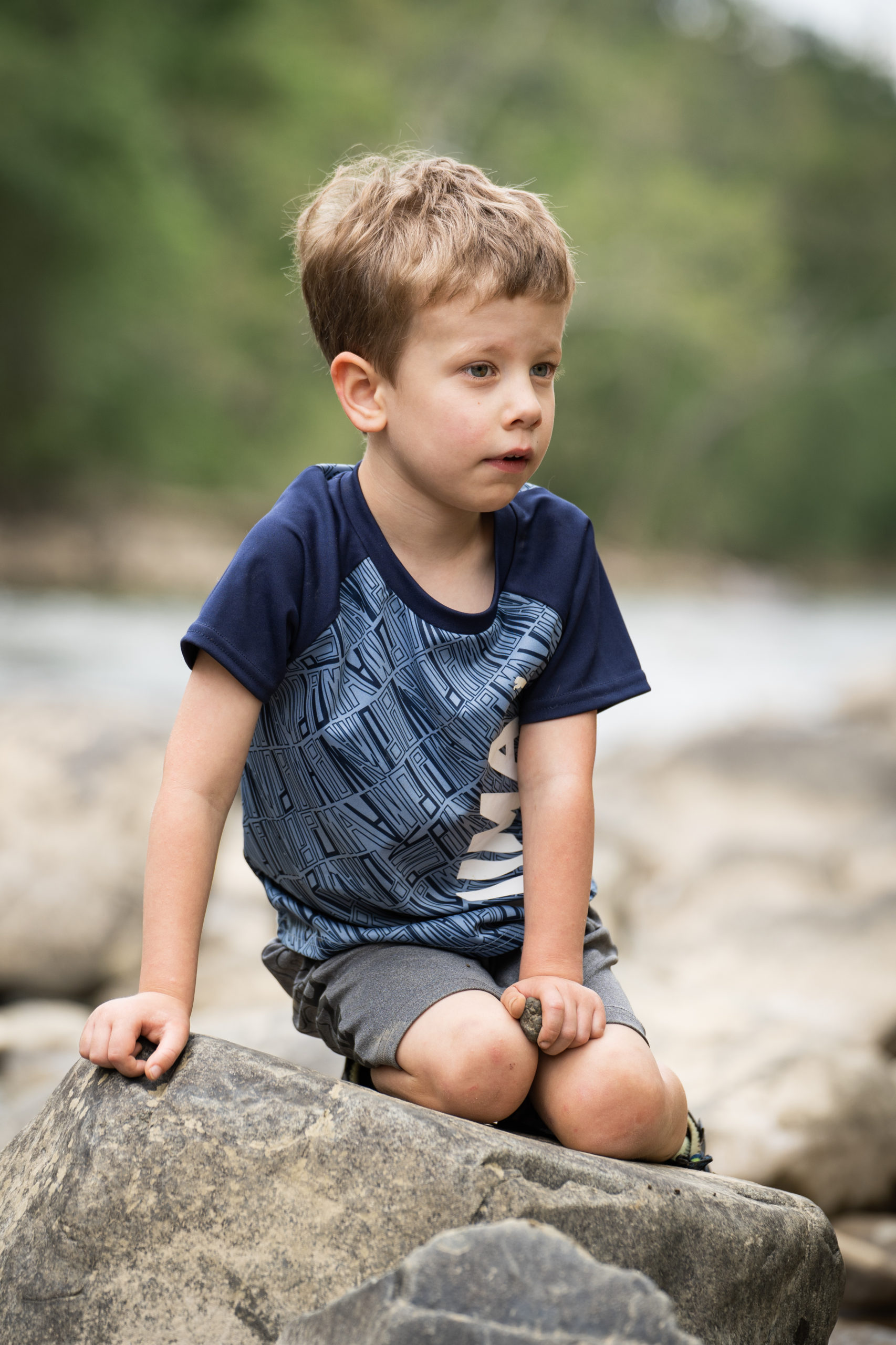 boy playing on rocks by creek