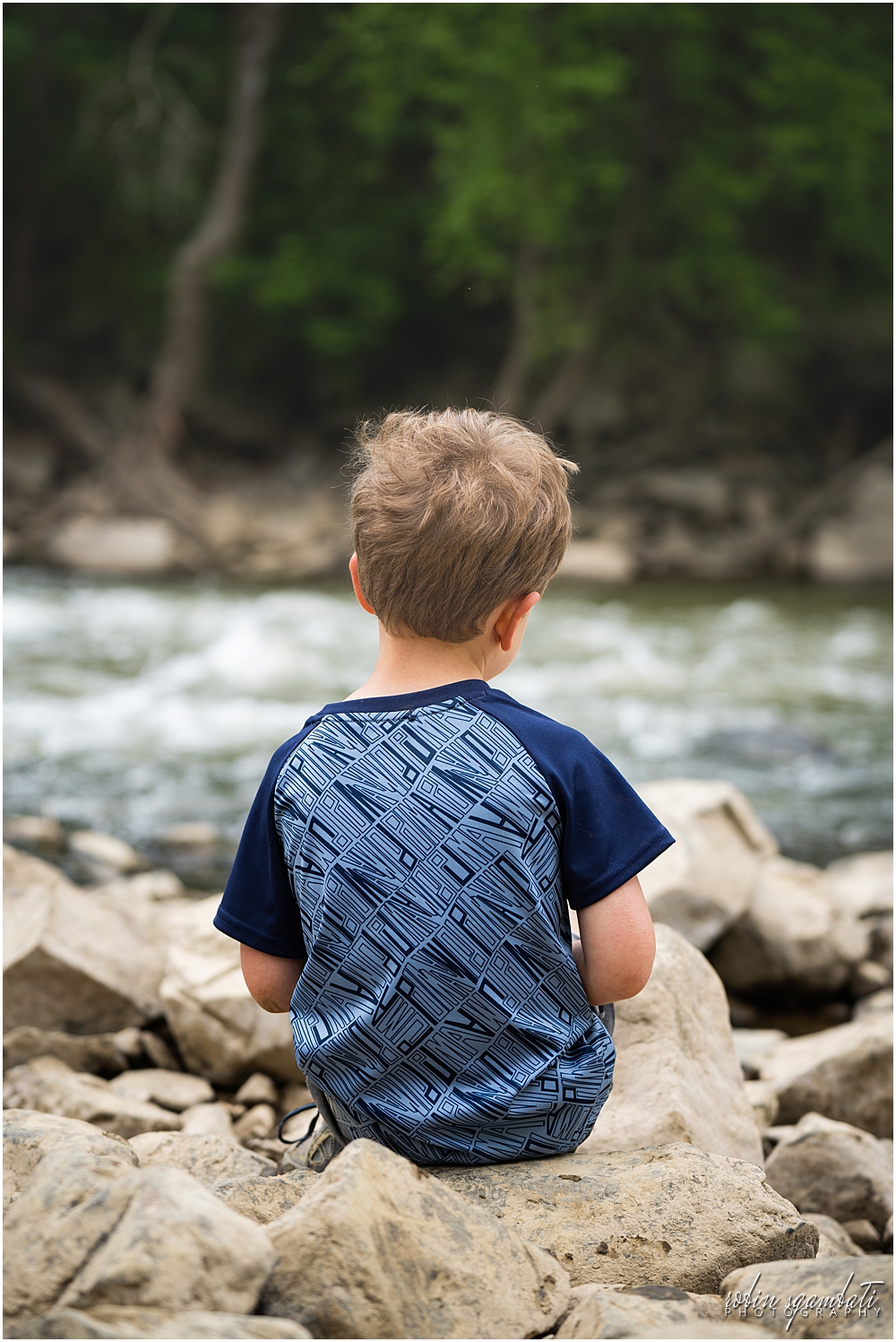 boy playing on rocks by creek