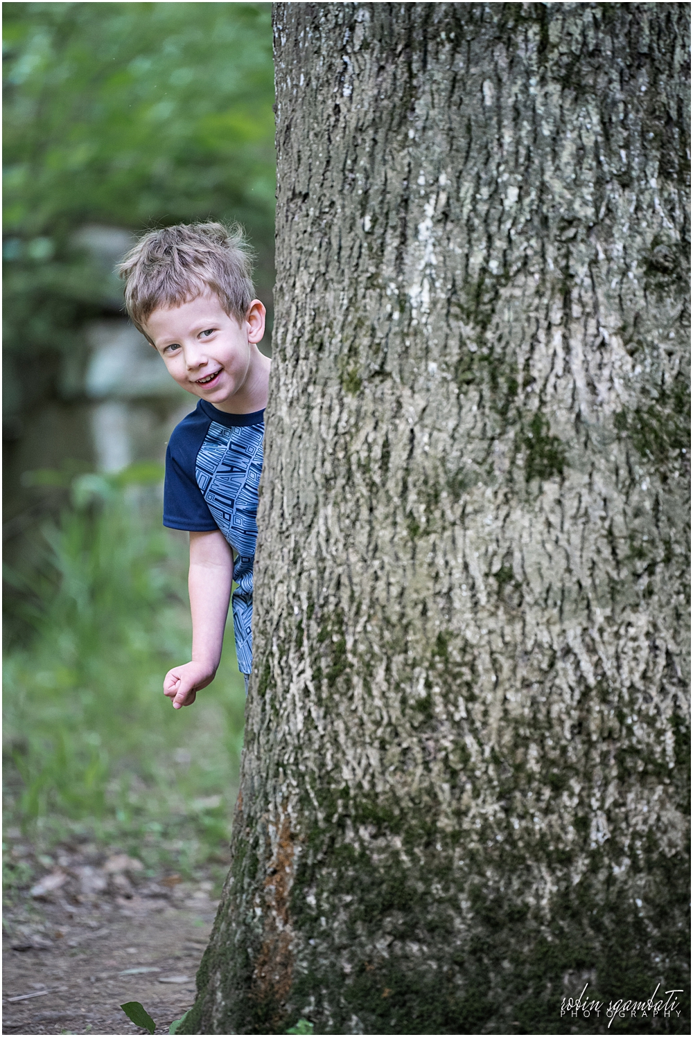 boy peeking from behind tree